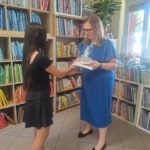 pani z biblioteki wręcza wolontariuszce dyplom i słodkie podziękowanie