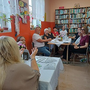 autorka siedzi przed grupą ludzi siedzących na krzesłach