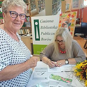 autorka podpisuje książkę a obok stoi kobieta