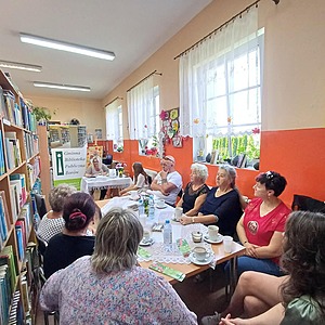 autorka siedzi przed grupą ludzi siedzących na krzesłach
