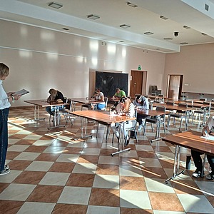 grupa ludzi siedzi w ławkach i pisze dyktando