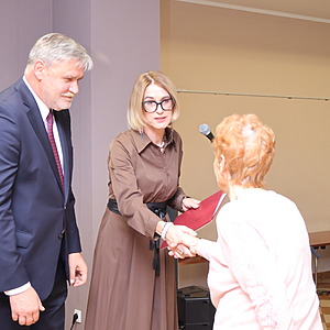 mężczyzna i dwie kobiety wręczają nagrodę kobiecie