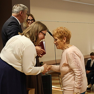mężczyzna i dwie kobiety wręczają nagrodę kobiecie