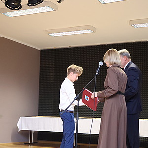 mężczyzna i kobieta wręczają nagrodę uczniowi