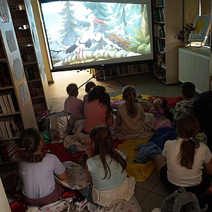 zdjęcie grupowe dzieci, które oglądają bajkę w bibliotece