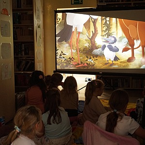 zdjęcie grupowe dzieci, które oglądają bajkę w bibliotece