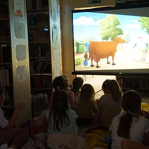 zdjęcie grupowe dzieci, które oglądają bajkę w bibliotece